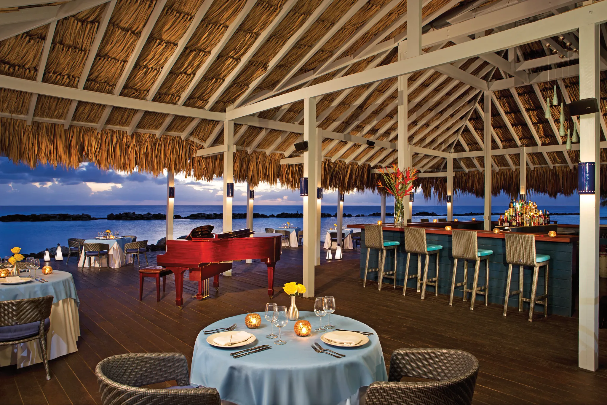Bluewater Grill seaside restaurant at Sunscape Curaçao Resort featuring open-air palapa dining, ocean views, and an elegant piano bar setting.
