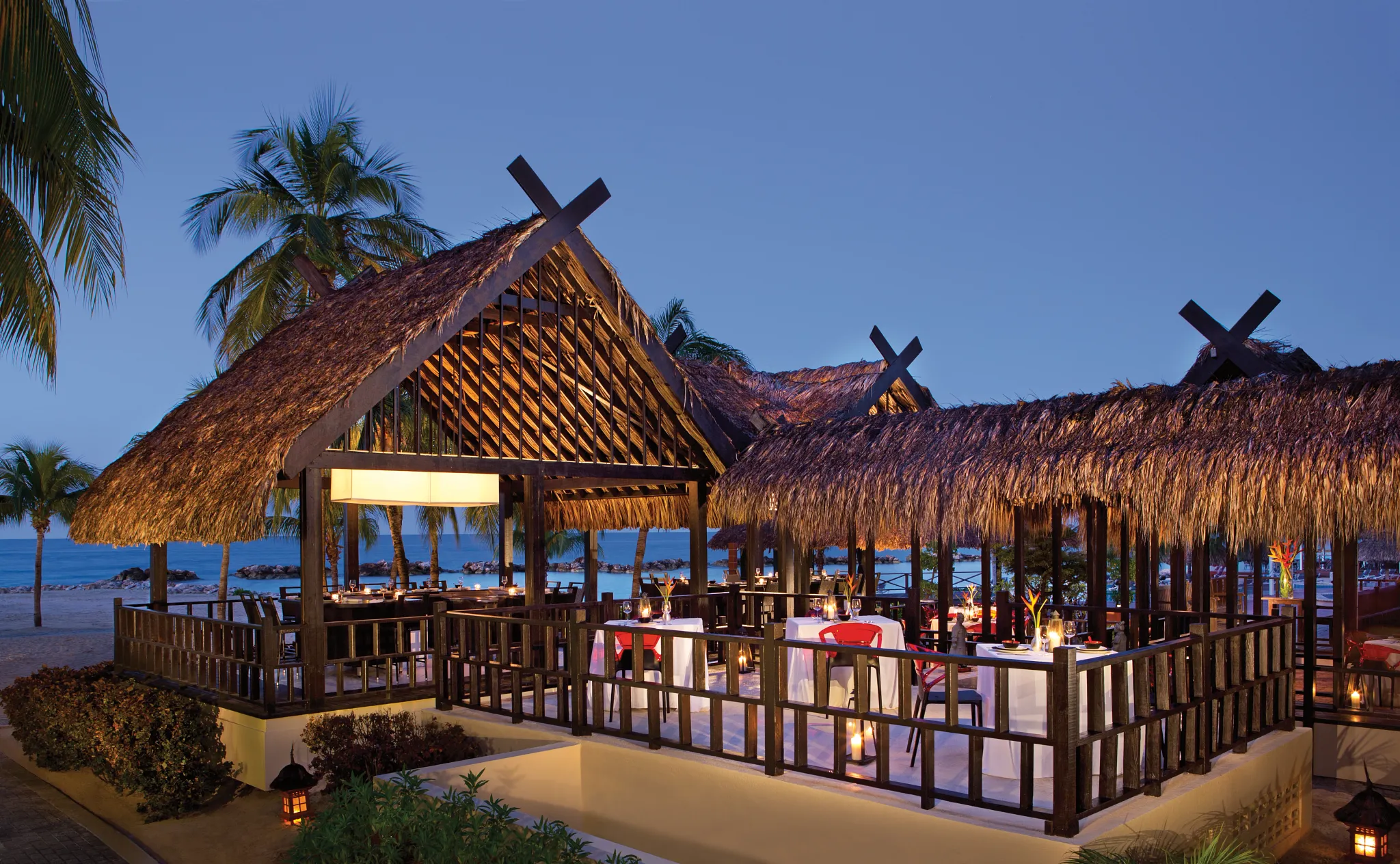 Himitsu Pan-Asian restaurant at Sunscape Curaçao Resort featuring open-air thatched-roof dining with ocean views and candlelit tables.
