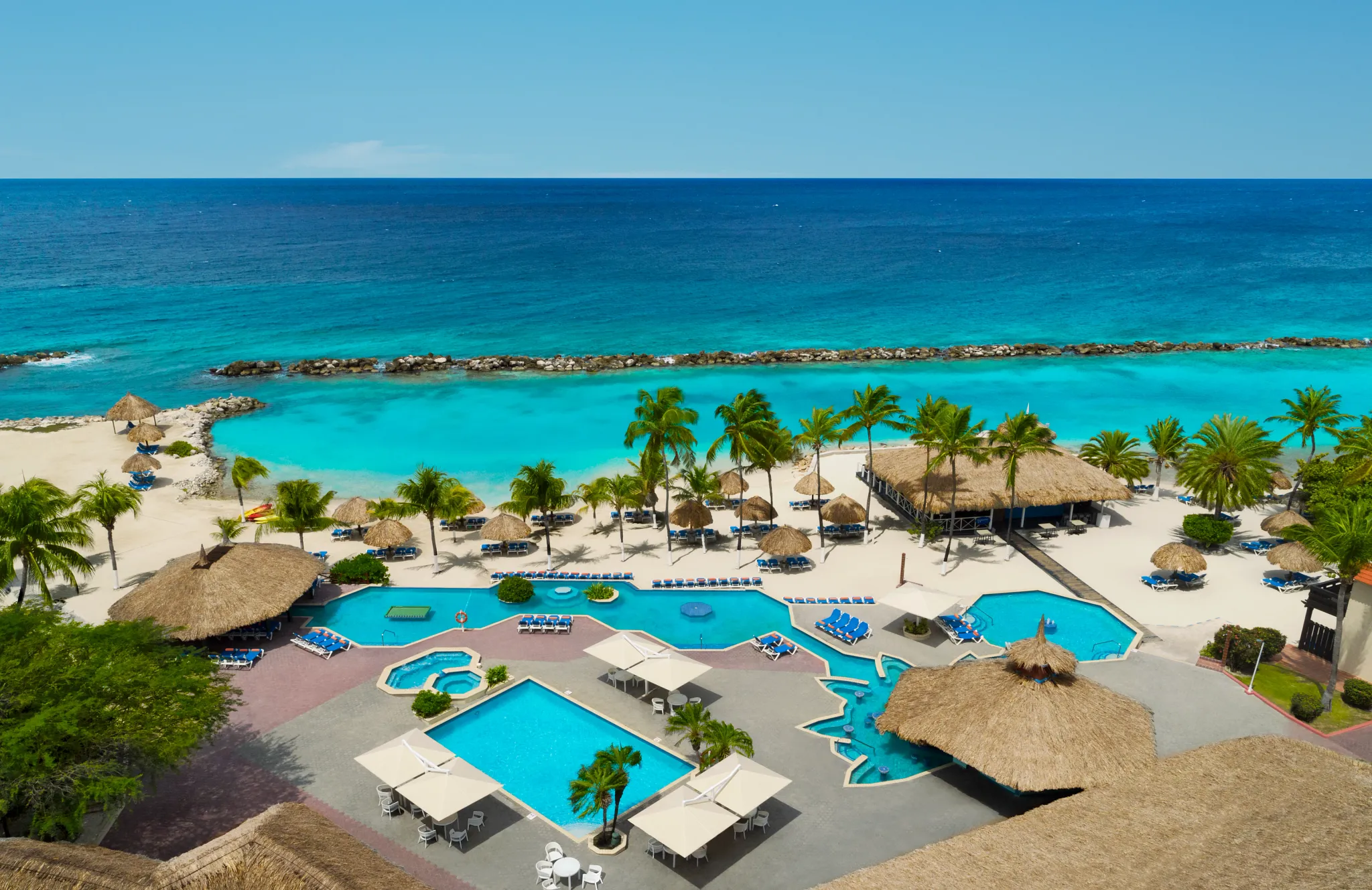 Resort pools and beachfront with palapa umbrellas at Sunscape Curaçao Resort, Spa & Casino in the Caribbean.