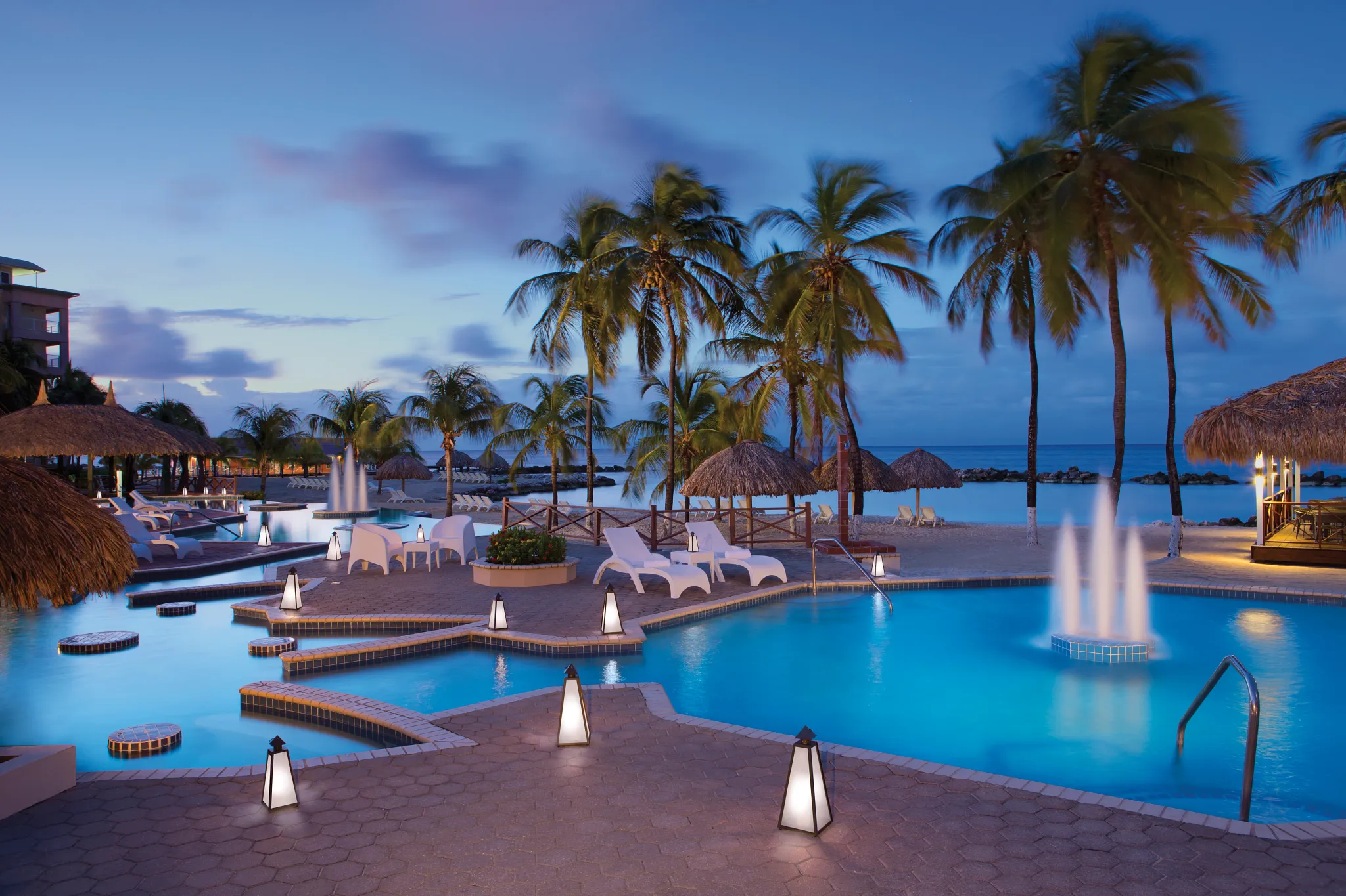 Resort pool illuminated at night with palm trees at Sunscape Curaçao Resort, Spa & Casino.