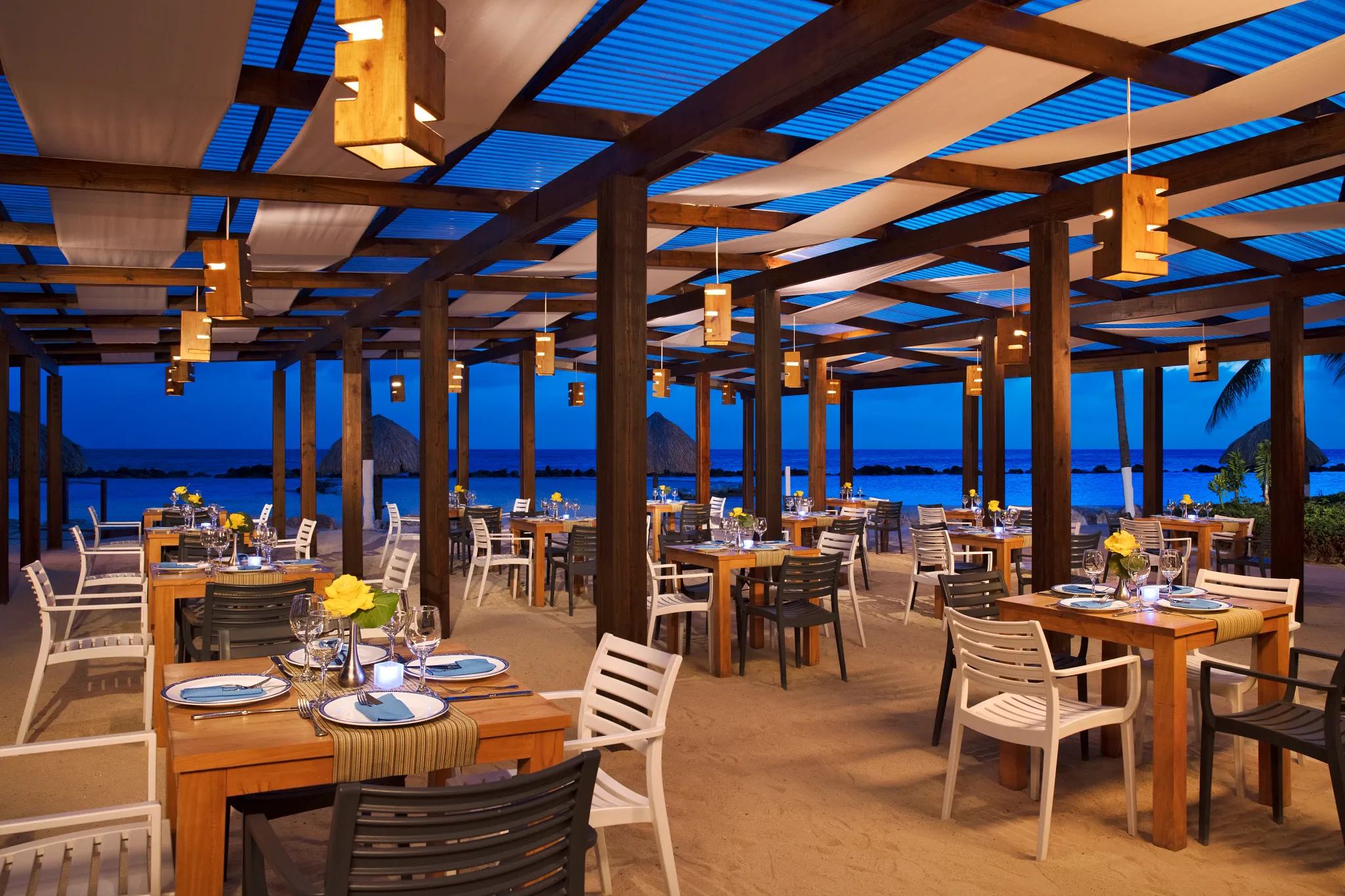 Oceana seafood restaurant at Sunscape Curaçao Resort featuring open-air beachfront dining with wooden pergola seating and ocean views at sunset.