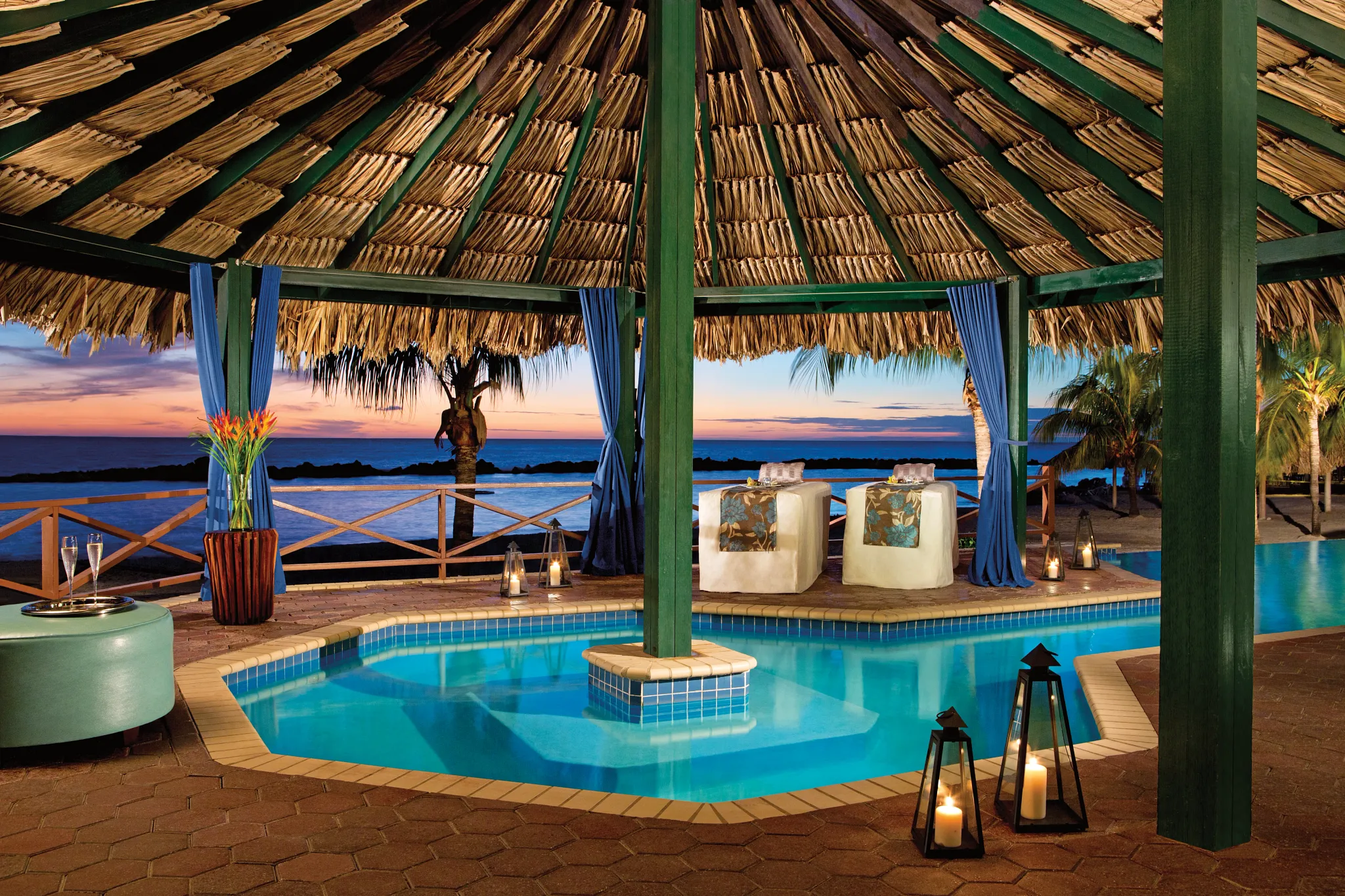 Oceanfront spa cabana with massage tables and candlelight at sunset at Sunscape Curaçao Resort, Spa & Casino.