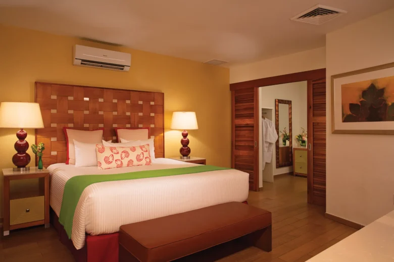 Presidential Suite bedroom with king-size bed, bedside lamps, and warm Caribbean décor at Sunscape Curaçao Resort.