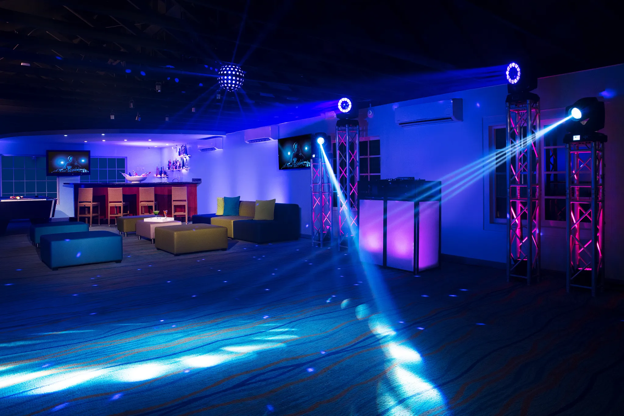 Starlight sports bar and music lounge at Sunscape Curaçao Resort featuring DJ booth, lounge seating, and colorful nightclub lighting.