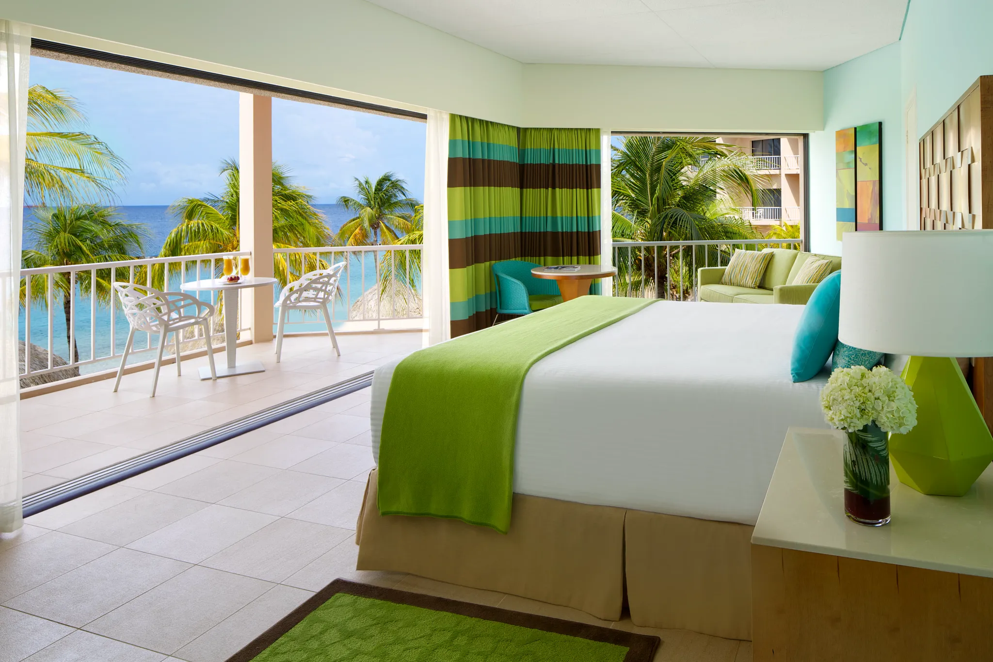 Sun Club Honeymoon Junior Suite Ocean Front king bedroom with seating area and ocean-view balcony at Sunscape Curaçao Resort.