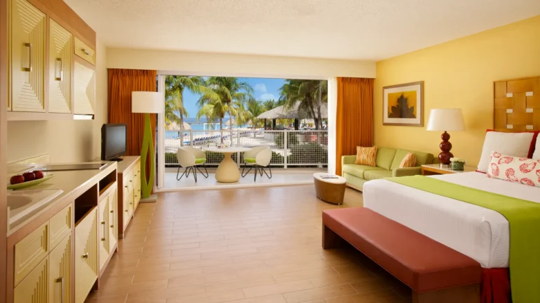 Sun Club Junior Suite Ocean View with king bed, sofa, and furnished balcony overlooking the Caribbean Sea at Sunscape Curaçao Resort.