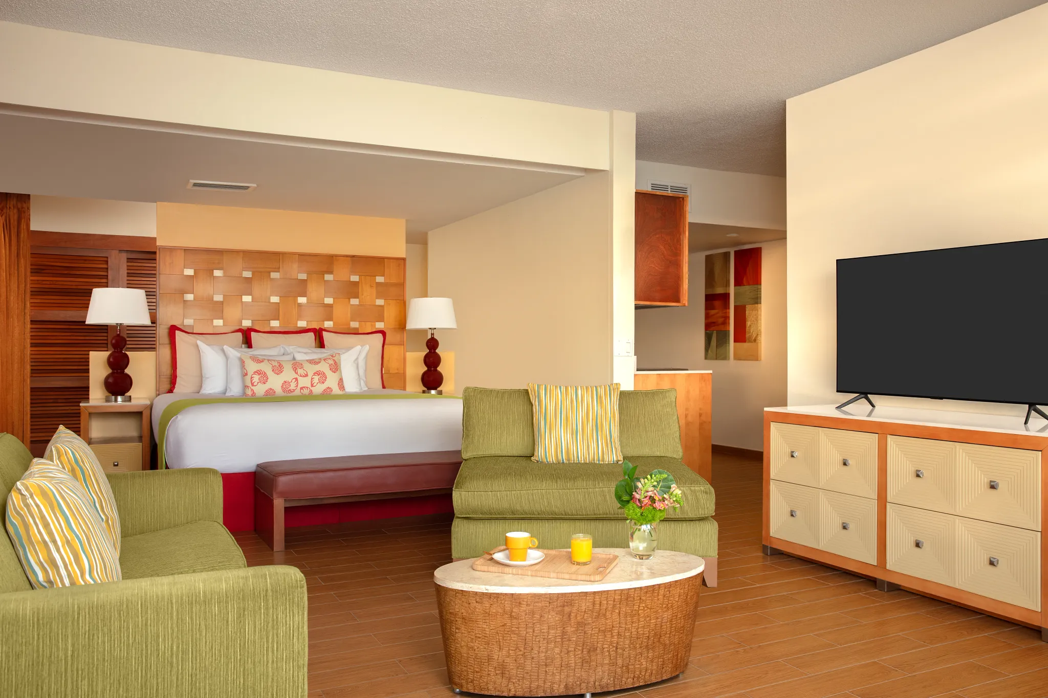 Sun Club Master Suite Ocean Front bedroom with king bed, bedside lamps, and tropical décor at Sunscape Curaçao Resort.
