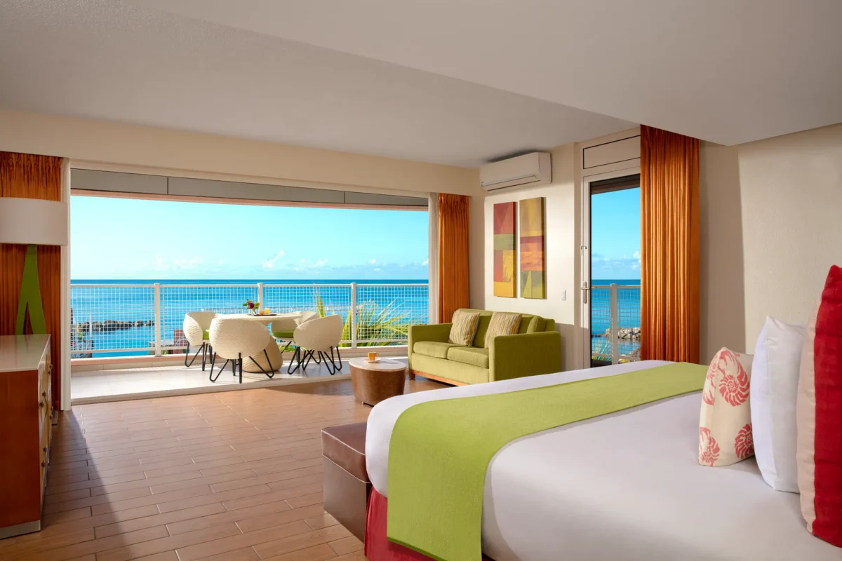 Sun Club Suite Ocean Front with queen bed, seating area, and private terrace overlooking the Caribbean Sea at Sunscape Curaçao Resort.